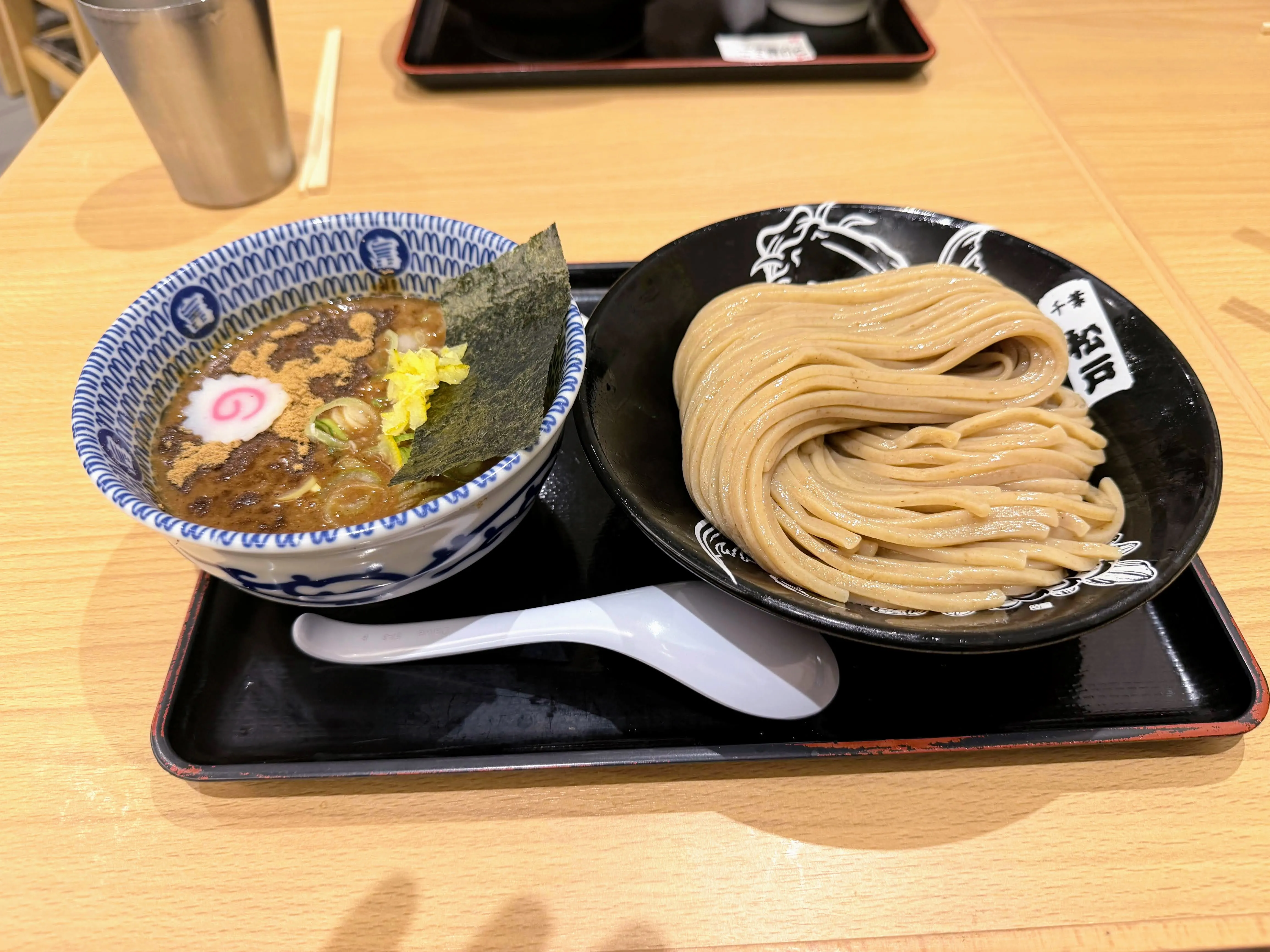 松戸中華そば富田食堂のつけ麺。中太麺と濃厚なつけ汁になると・海苔・柚子皮が添えられている
