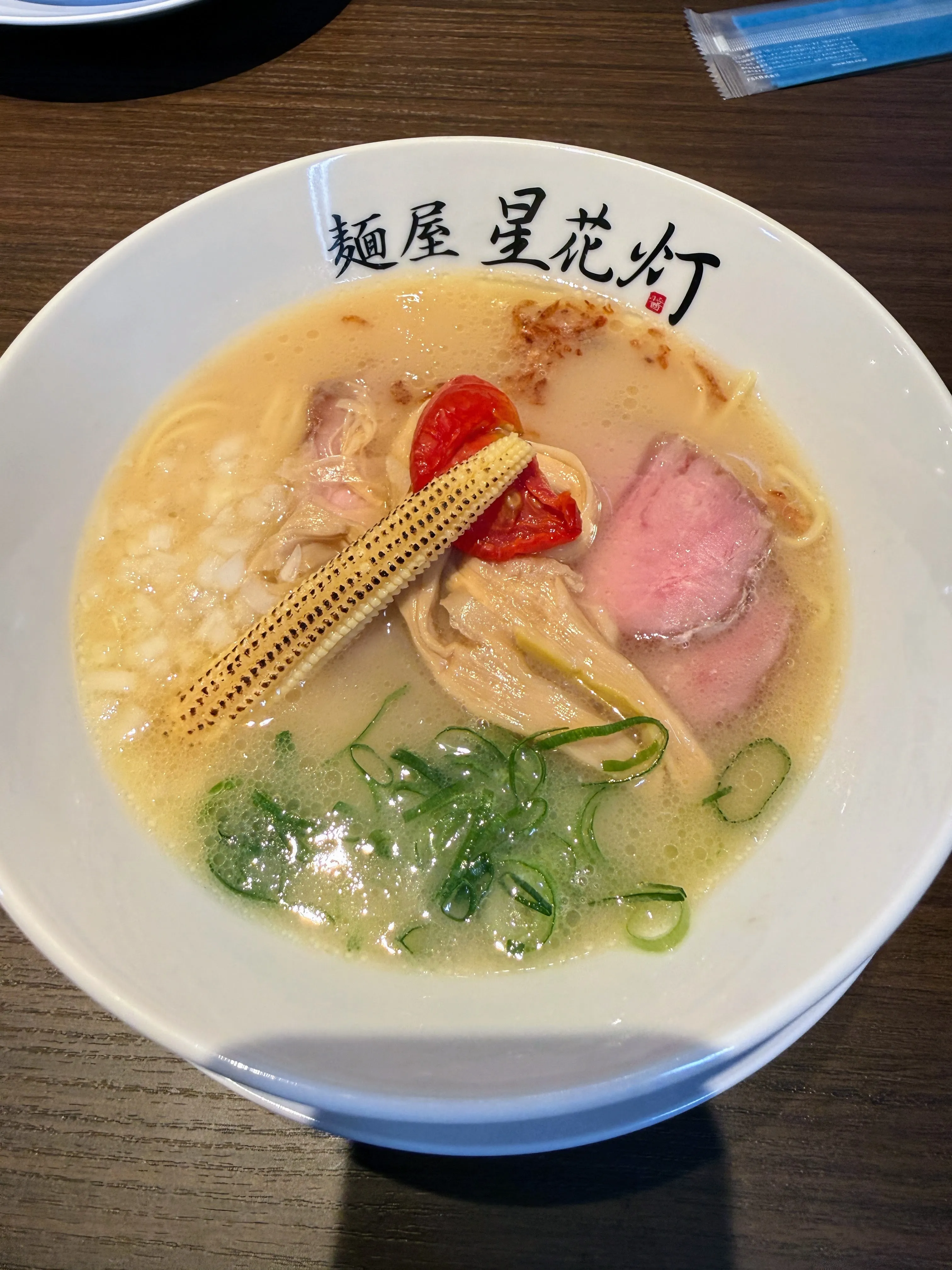 麺屋星花灯の白湯。鶏肉と厚切りチャーシュー、焼きトマト、コーンがのっている